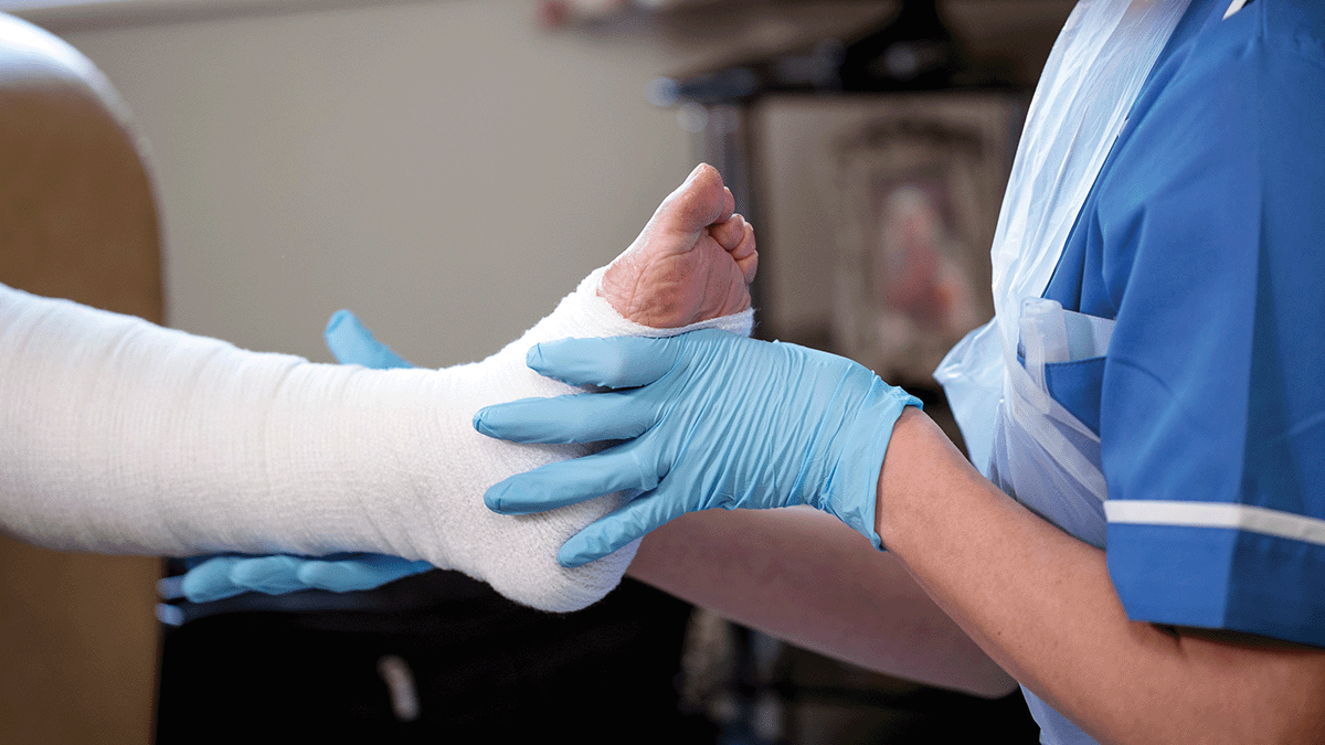 A nurse applying a dressing to a patient's leg. 