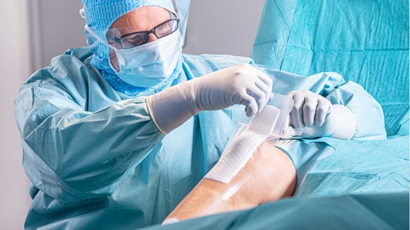 Kirurgi asettamassa sidosta leikkauksen jälkeen