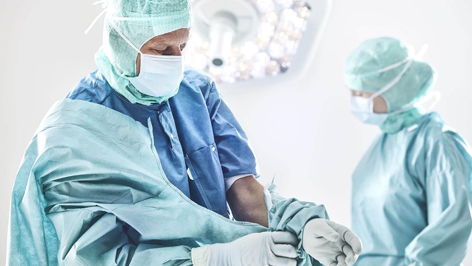Хирург, надевающий хирургический халат до операции